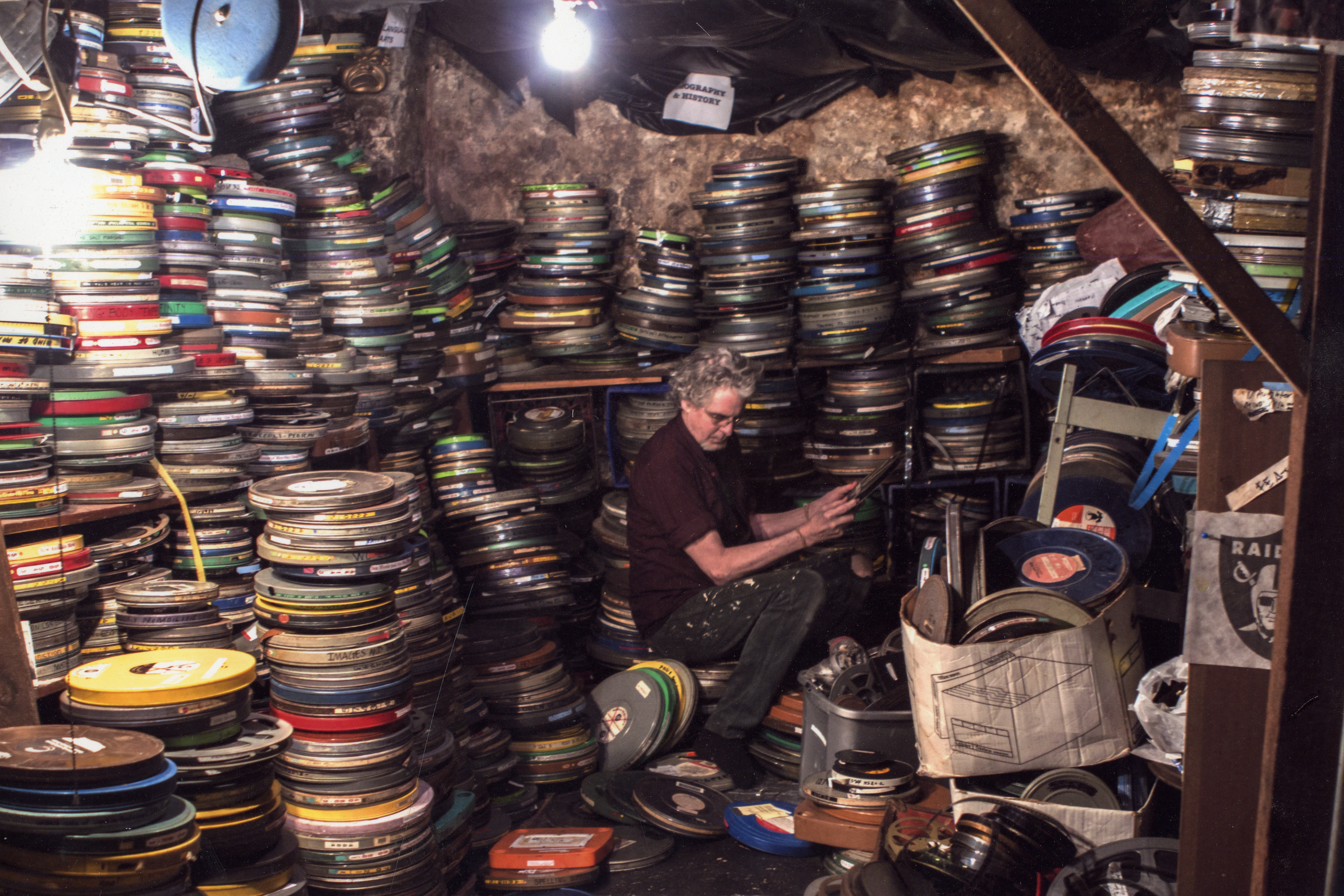 Experimental filmmaker Craig Baldwin surrounded by cans of film reels