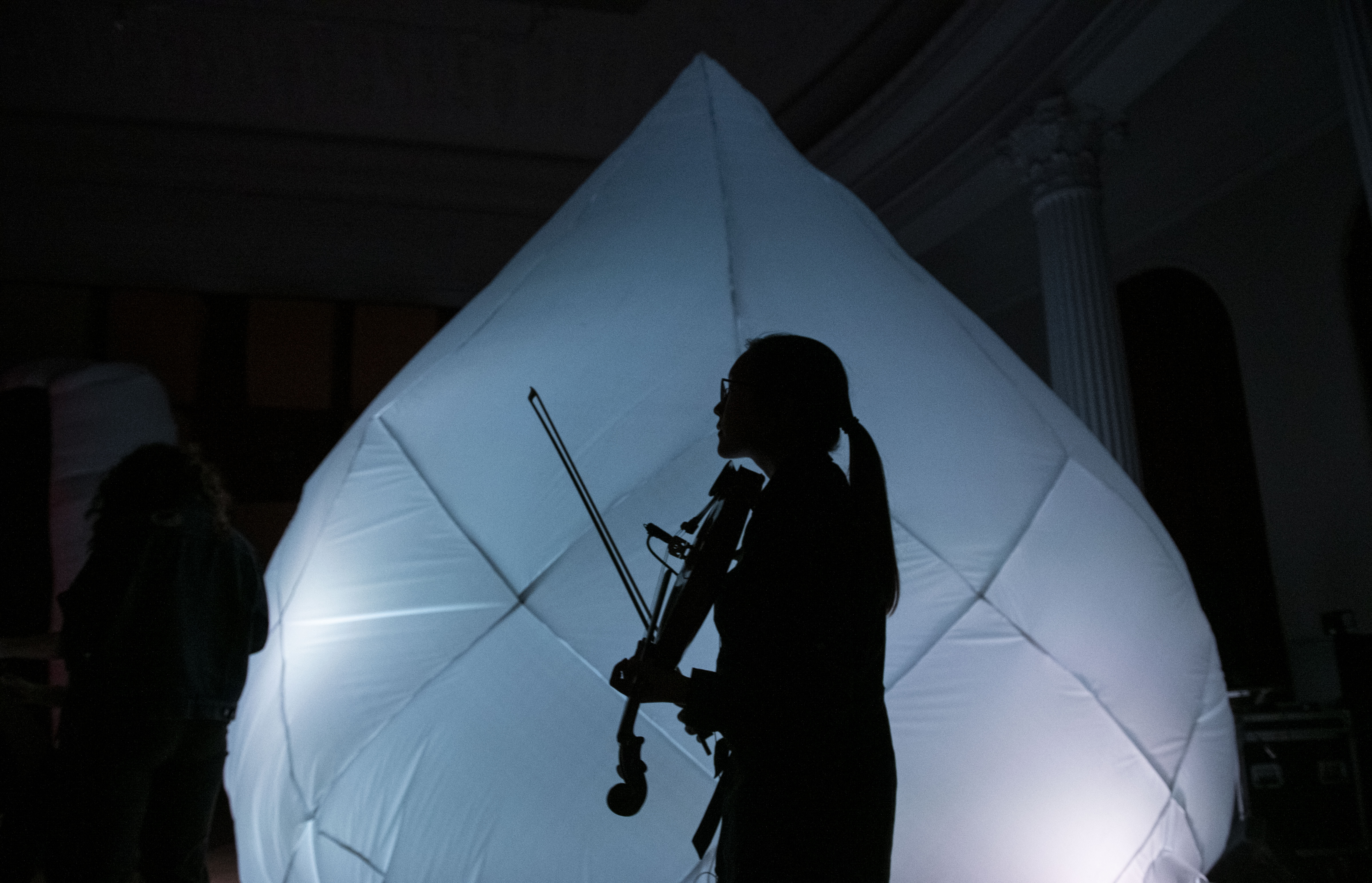 Student playing violin in front of inflatable sculpture